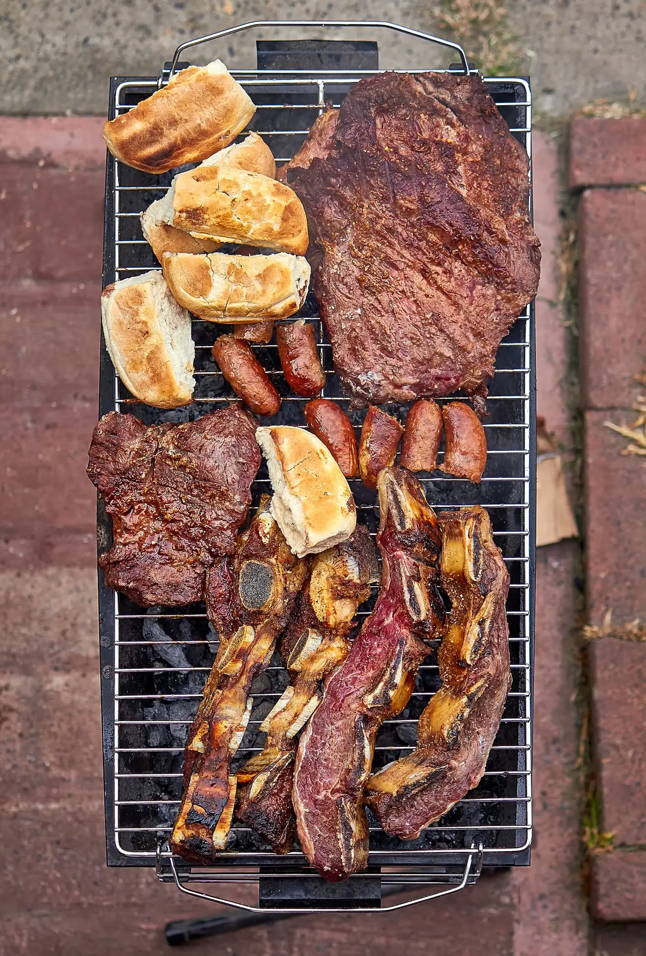 Parrillada completa con cortes de res, chorizo y quesos sobre una parrilla
